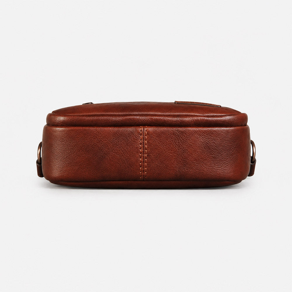 Bottom view of deep brown full-grain leather waist bag showing structured base, reinforced seams, and compact profile
