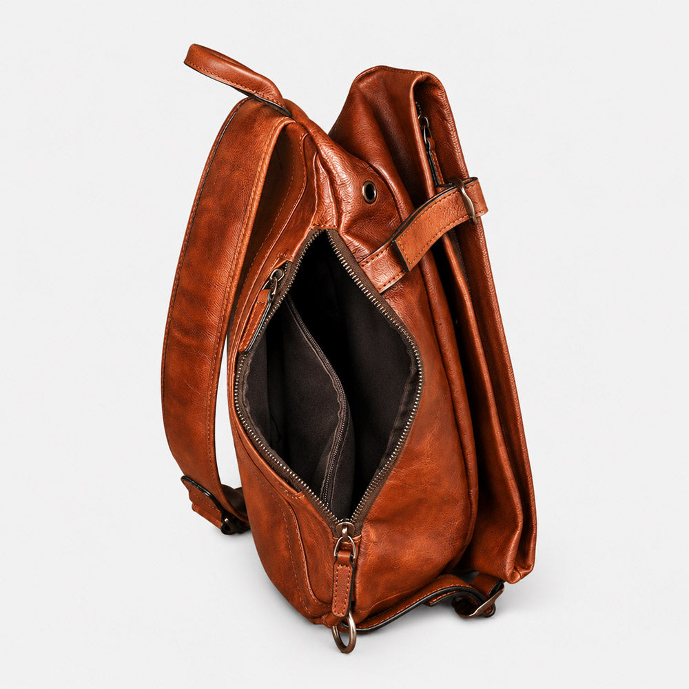 Open interior of brown leather shoulder bag showing space for an 11-inch tablet, mirrorless camera, wallet, and travel essentials