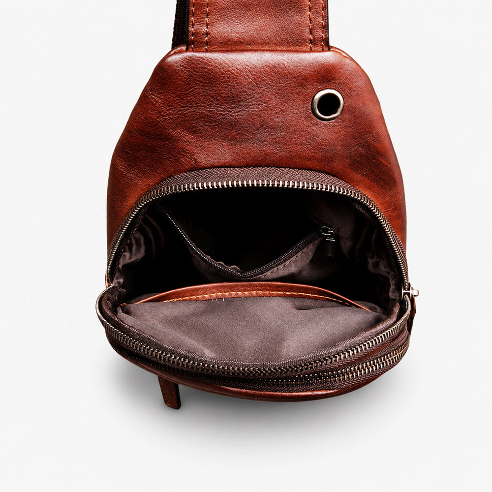 Open deep brown leather fanny pack showing organized interior space for a 9-inch tablet, wallet, phone, and essentials